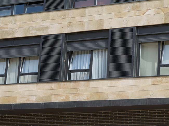 Un edificio con muchas ventanas y persianas negras.