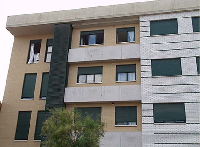 Un edificio con muchas ventanas y persianas verdes.