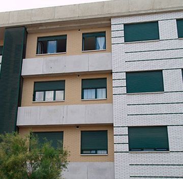 Un edificio con muchas ventanas y persianas verdes.