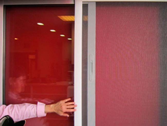 Una persona está abriendo una puerta corrediza de vidrio con un fondo rojo.