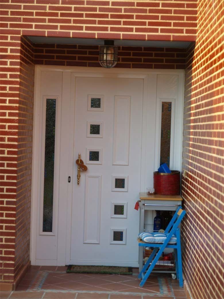 Un edificio de ladrillo con una puerta blanca y una silla azul.
