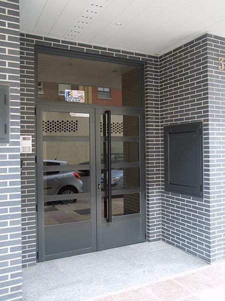 Un edificio de ladrillo con una puerta de vidrio y un buzón.