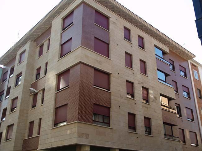 Un edificio grande con muchas ventanas y persianas rojas.