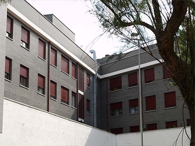 Un gran edificio con un árbol delante.