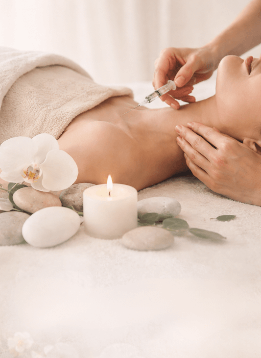 Eine Person, die sich in einem Spa eine Nackeninjektion geben lässt; Kerze und Blumen sind vorhanden.