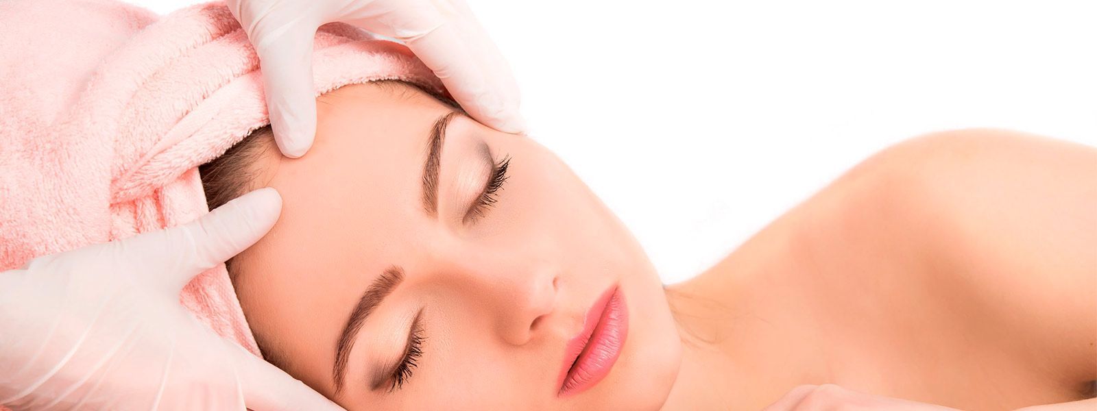 Una mujer con una toalla envuelta alrededor de su cabeza está recibiendo un tratamiento facial.