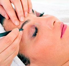 Una mujer se está afeitando las cejas en un salón de belleza.