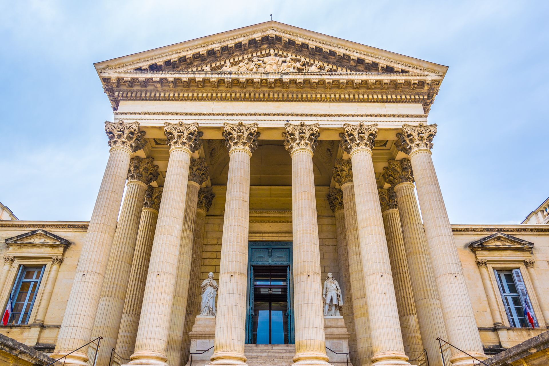 Palais de justice avec de grandes colonnes, un fronton triangulaire et des portes bleues.