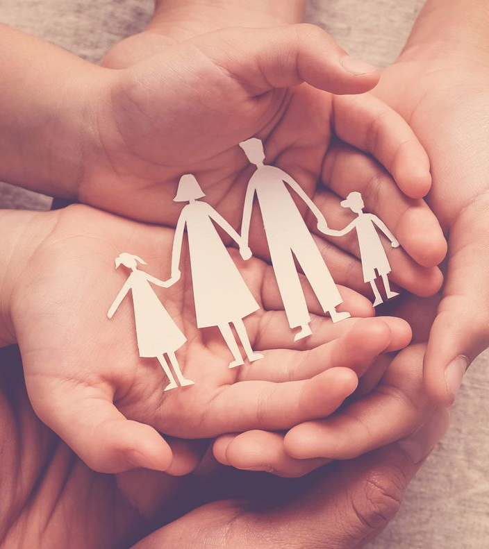 Mains tenant une découpe en papier représentant une famille.
