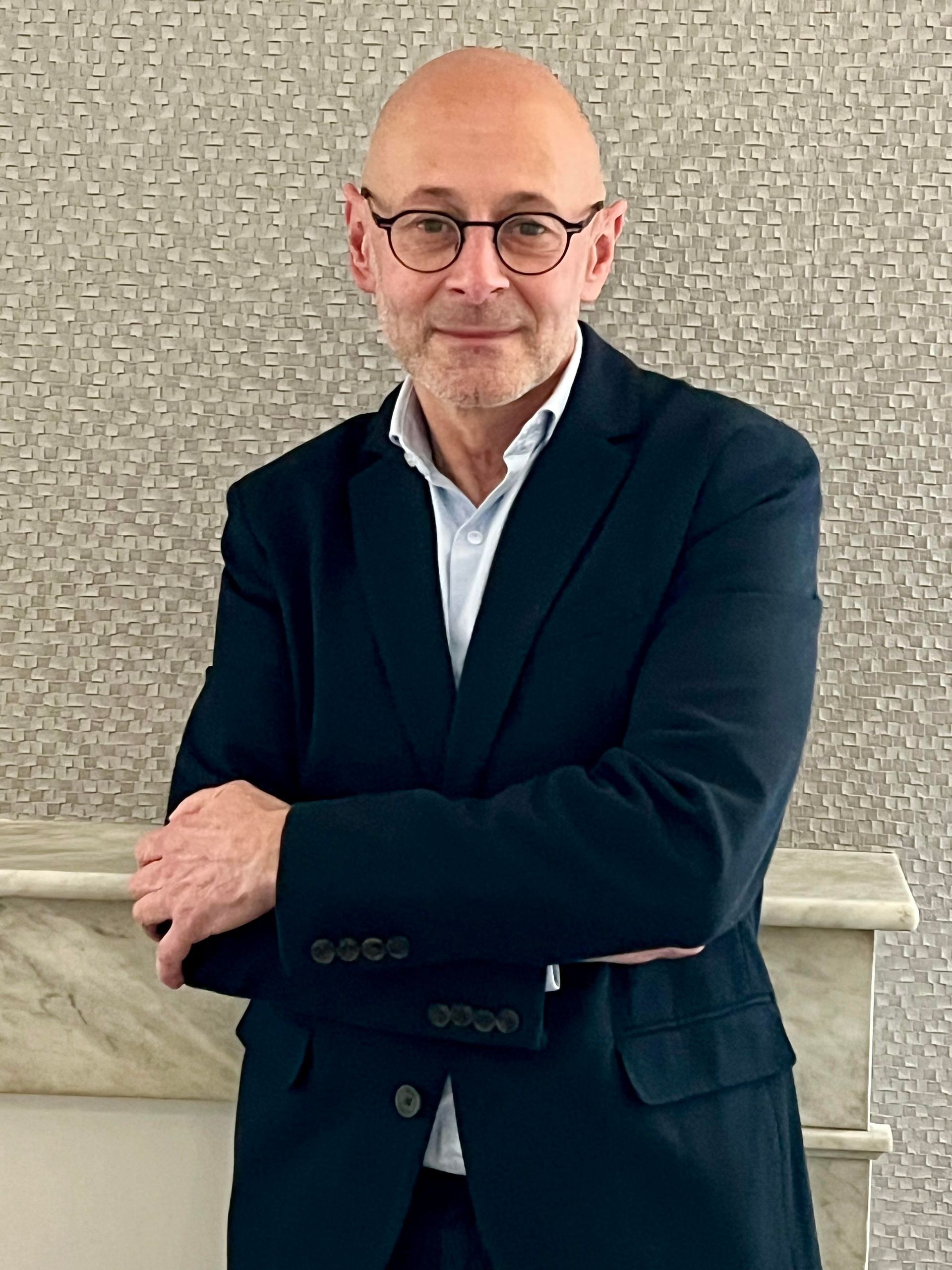 Un homme en costume et portant des lunettes est assis à un bureau.