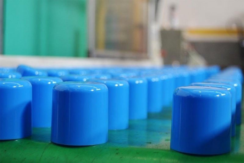 Una fila de cilindros de plástico azules colocados encima de una mesa verde.