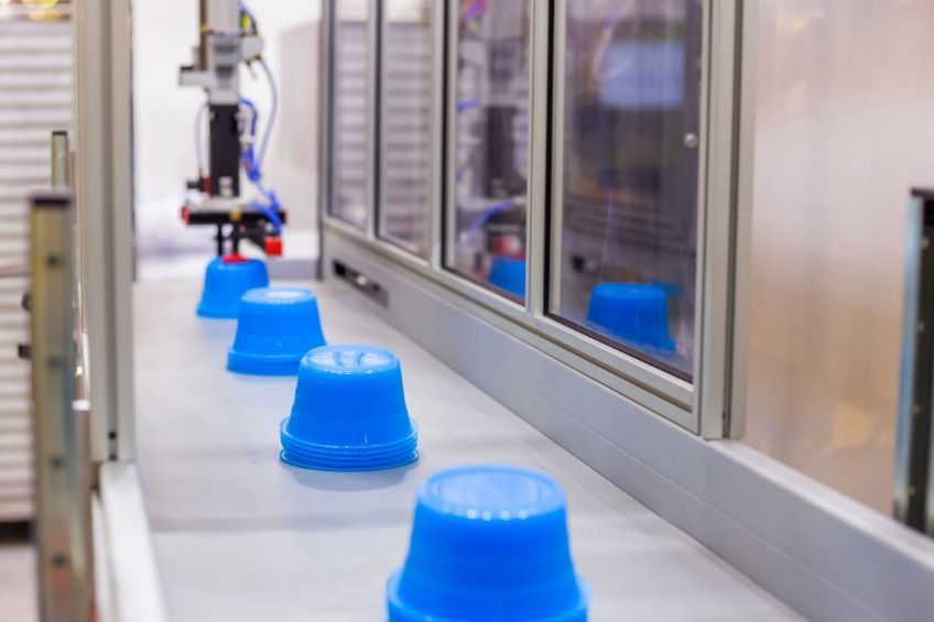 Una cinta transportadora llena de vasos de plástico azules en una fábrica.