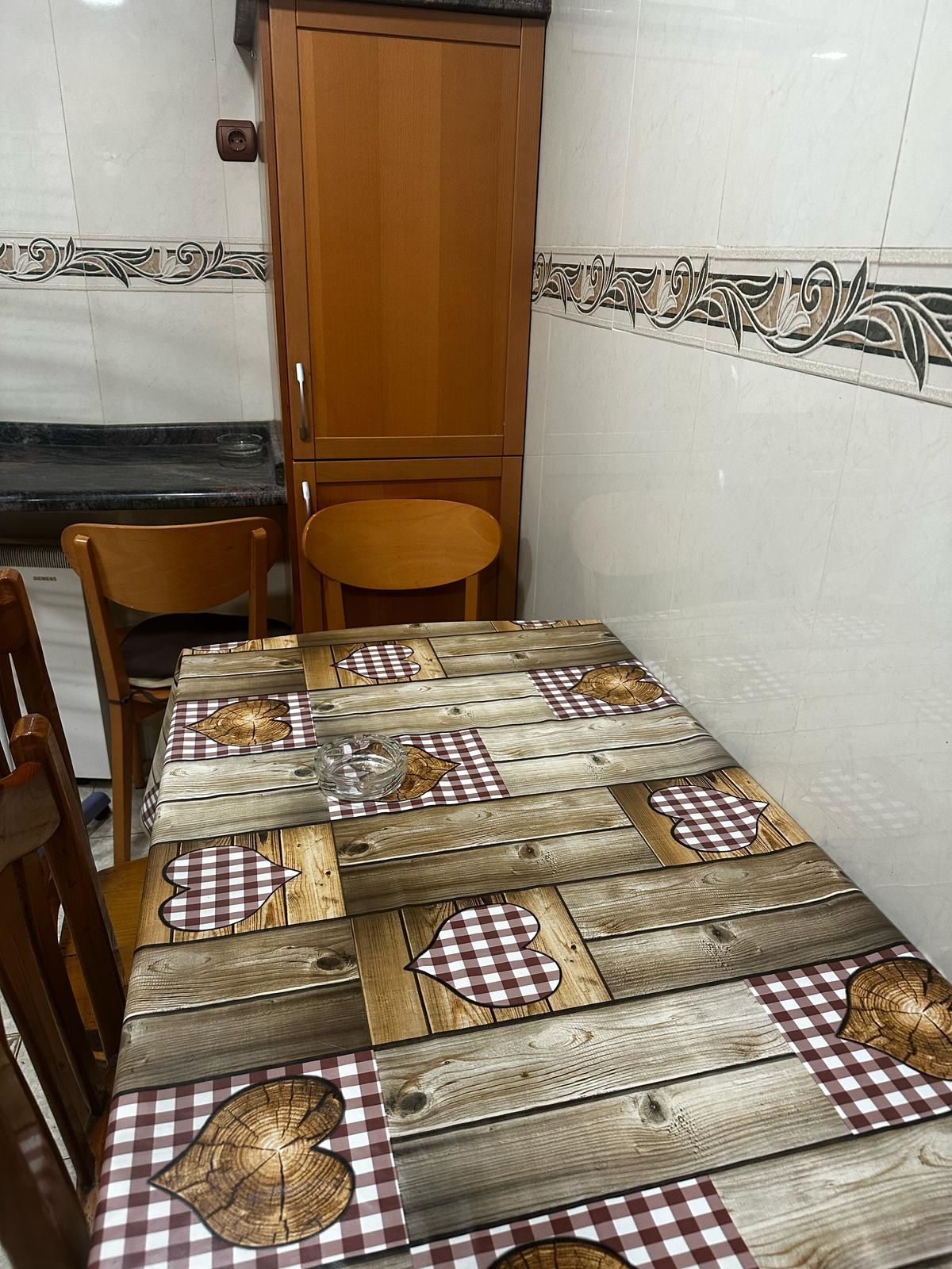 Una mesa de madera con un mantel a cuadros en una cocina.
