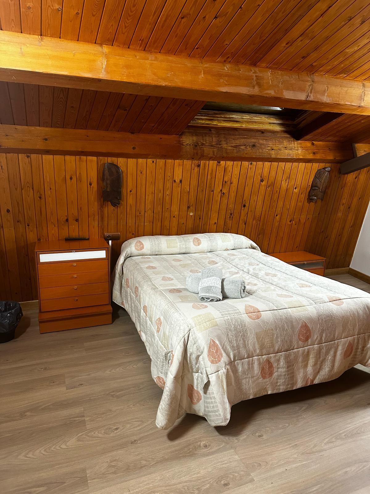 Un dormitorio con techo de madera y una cama.