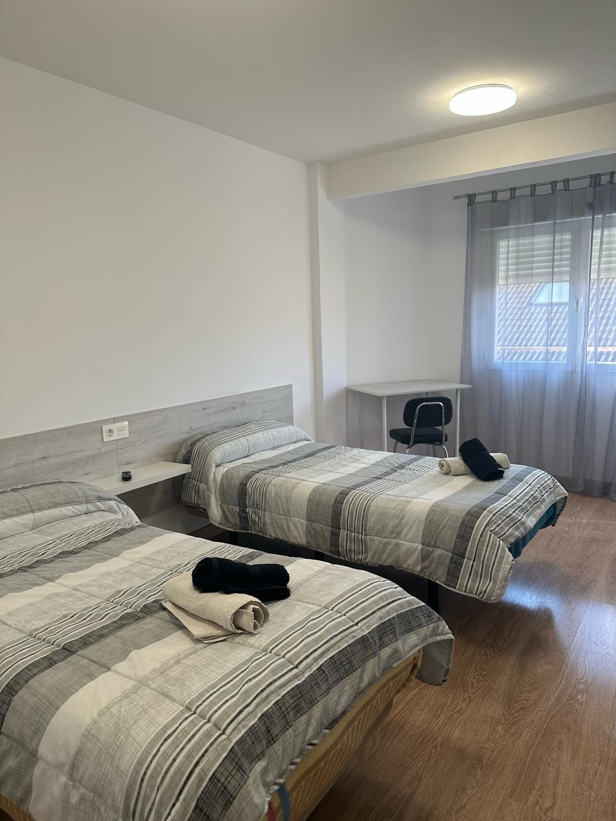 Un dormitorio con dos camas, un escritorio y una ventana.