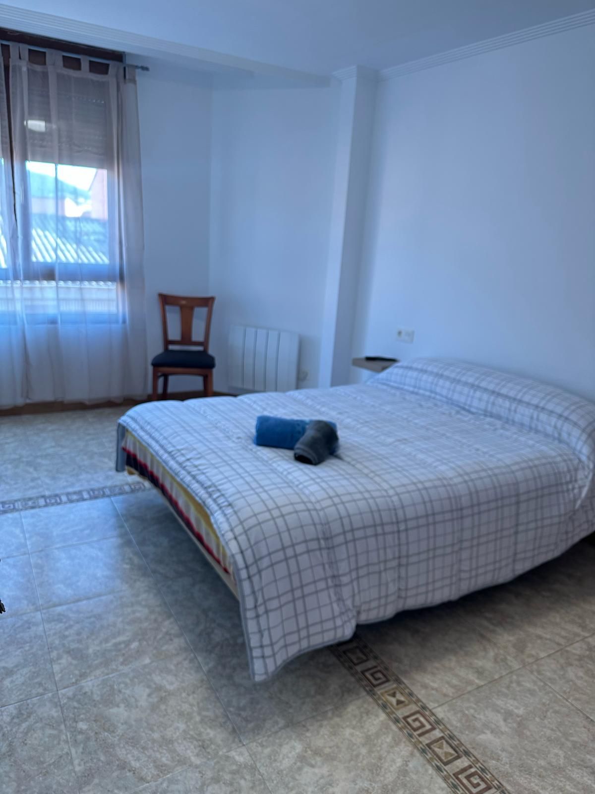 Un dormitorio con una cama grande y una silla.