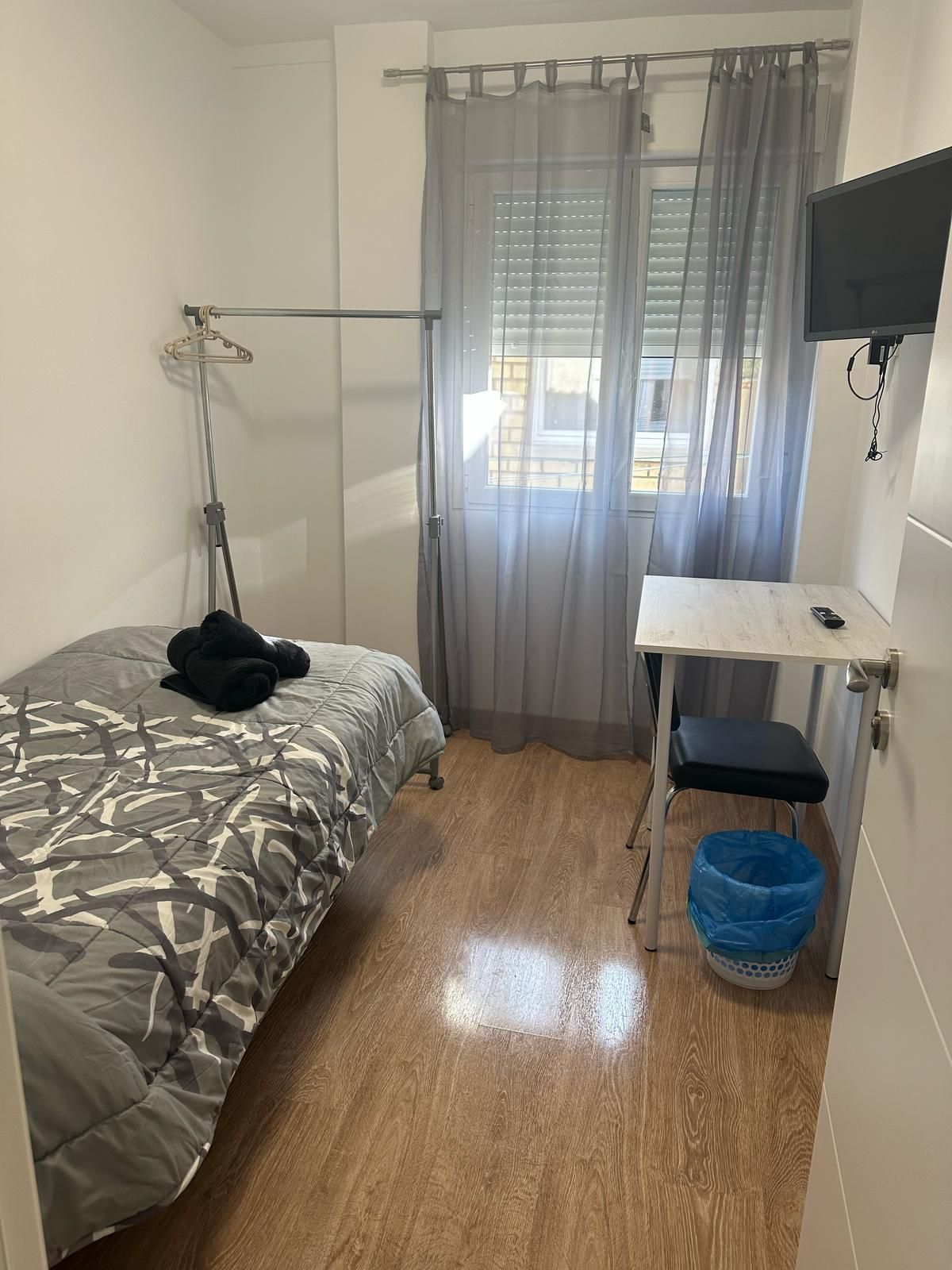 Un dormitorio con una cama, un escritorio y un televisor.