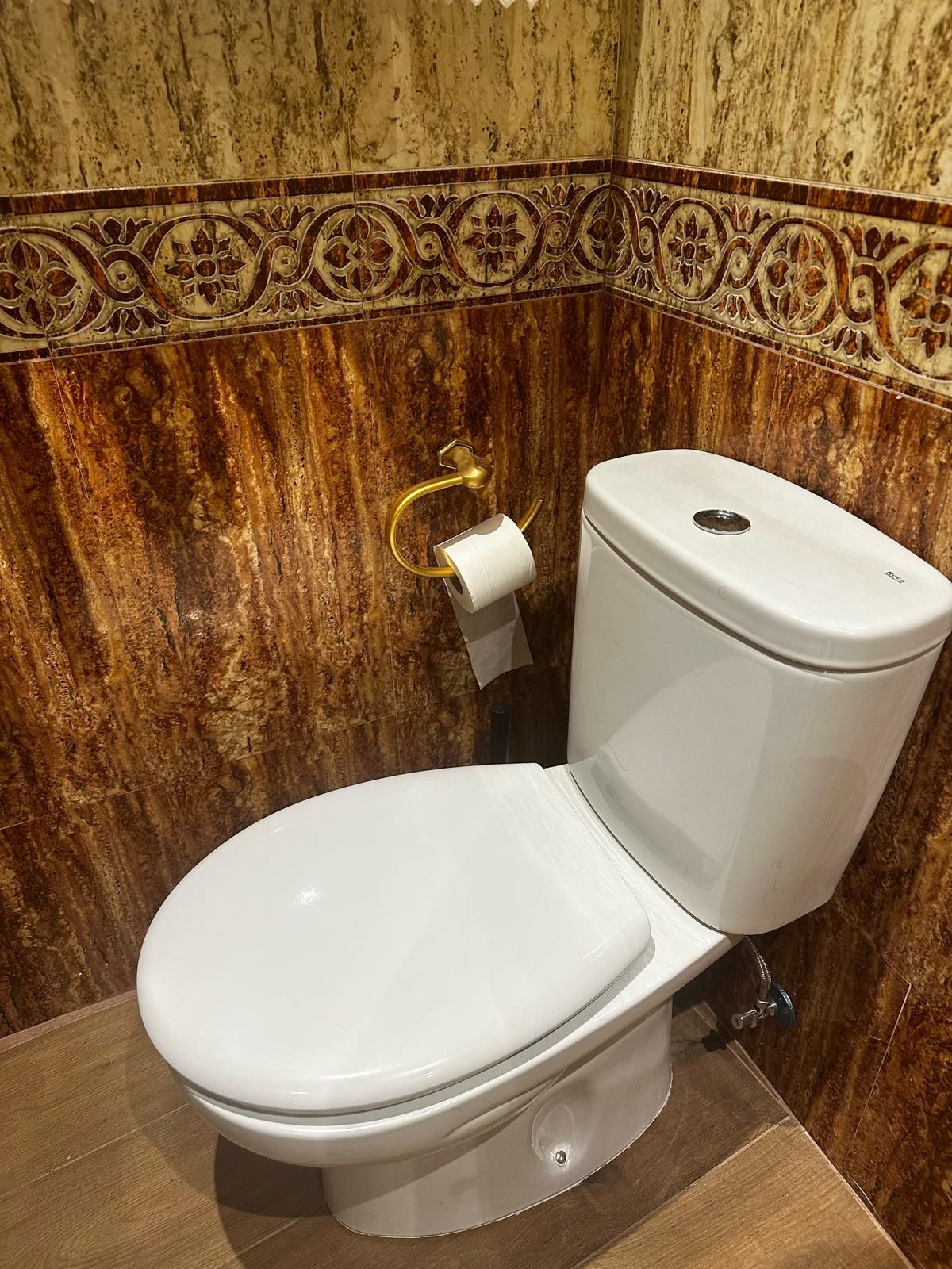 Un inodoro se encuentra en un baño al lado de un soporte para toallas de papel.