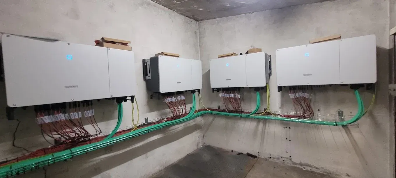 Hilera de cajas de control eléctrico montadas en la pared con cableado expuesto en un cuarto de servicio.
