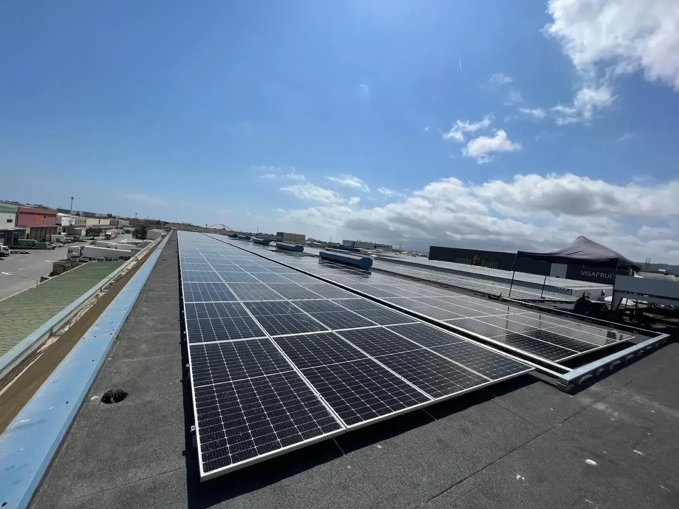 Paneles solares instalados en una azotea bajo un cielo azul brillante con nubes dispersas.
