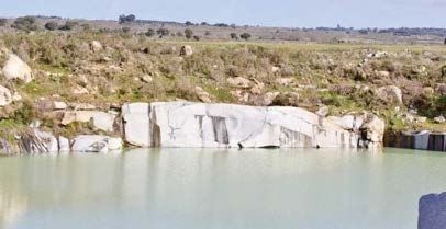 Un hombre está parado frente a un lago rodeado de rocas.