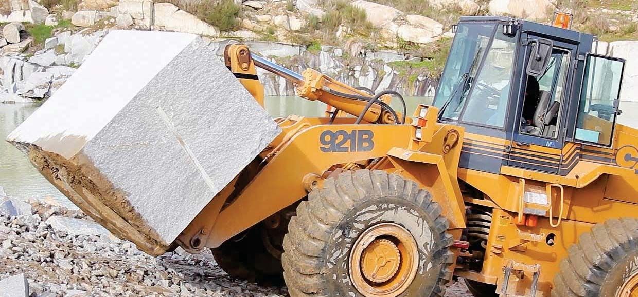 Una excavadora transporta una gran roca en una cantera.