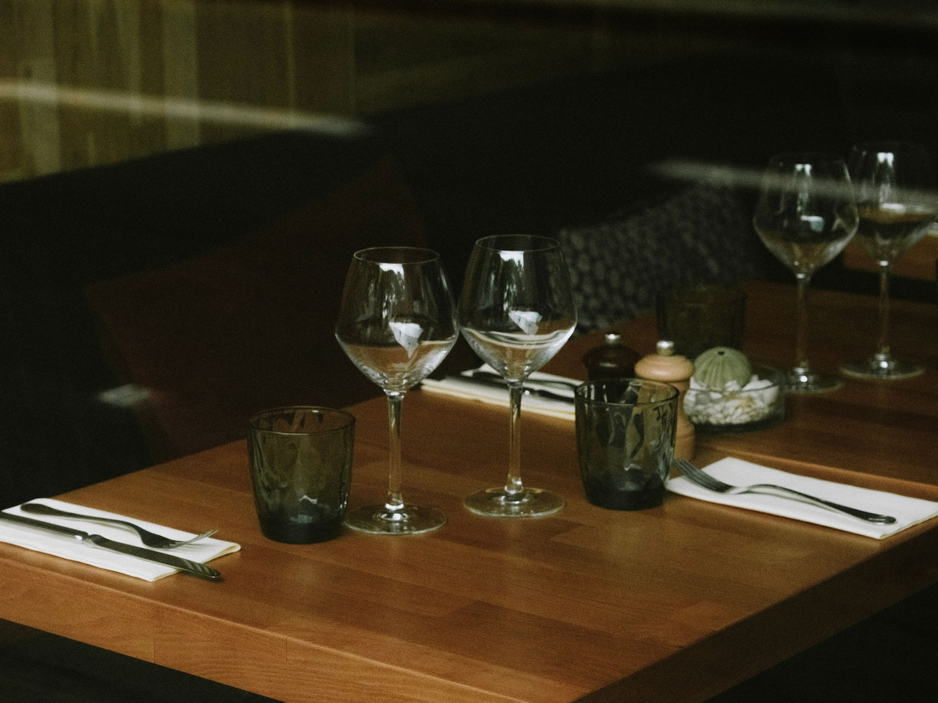 Dresser une table à manger avec des verres à vin, des verres à eau, des bougies et des serviettes dans un restaurant à l'ambiance tamisée