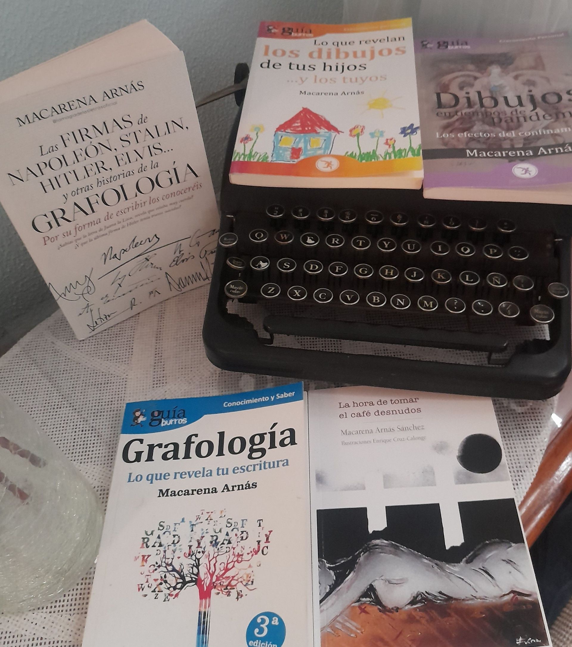 Una máquina de escribir rodeada de libros, incluido uno titulado Grafología.