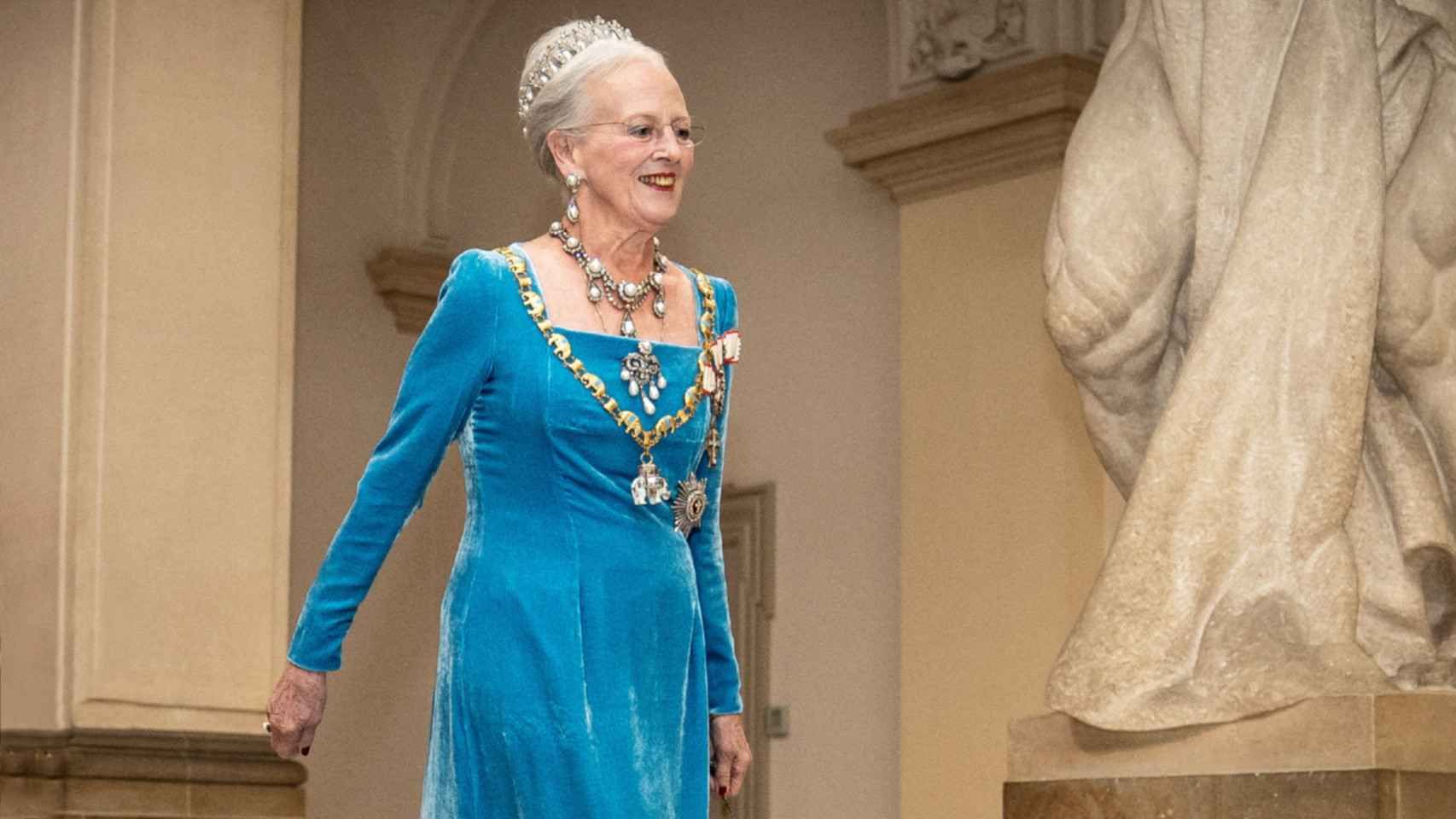 Una mujer con un vestido azul está parada junto a una estatua.
