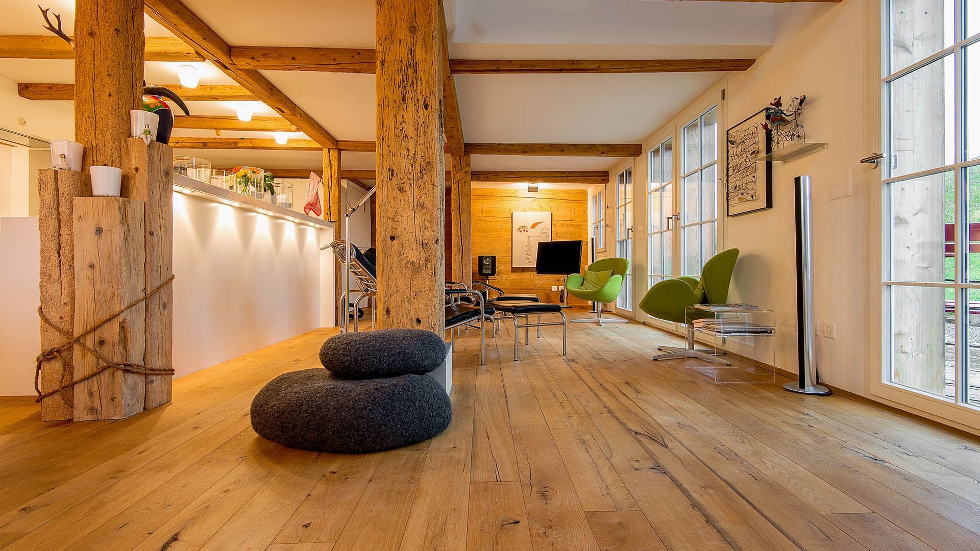 Ein Wohnzimmer mit Holzboden und vielen Fenstern.