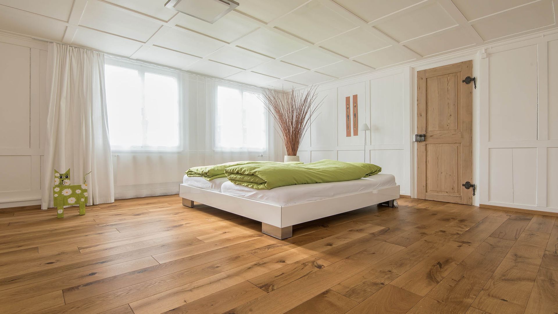 In der Mitte des Zimmers steht ein Bett mit Holzboden.