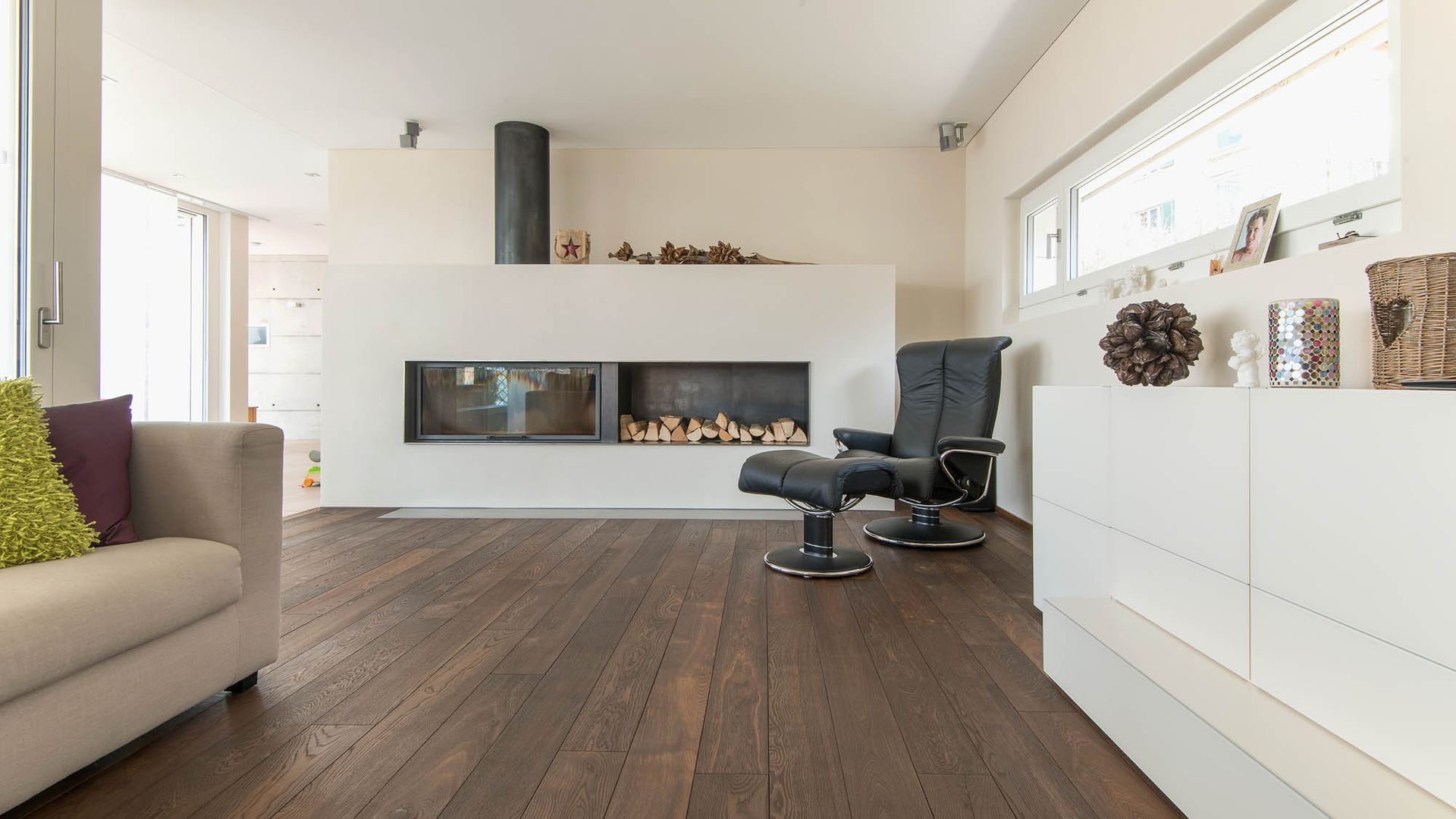 Ein Wohnzimmer mit Hartholzböden, einer Couch, einem Sessel und einem Kamin.