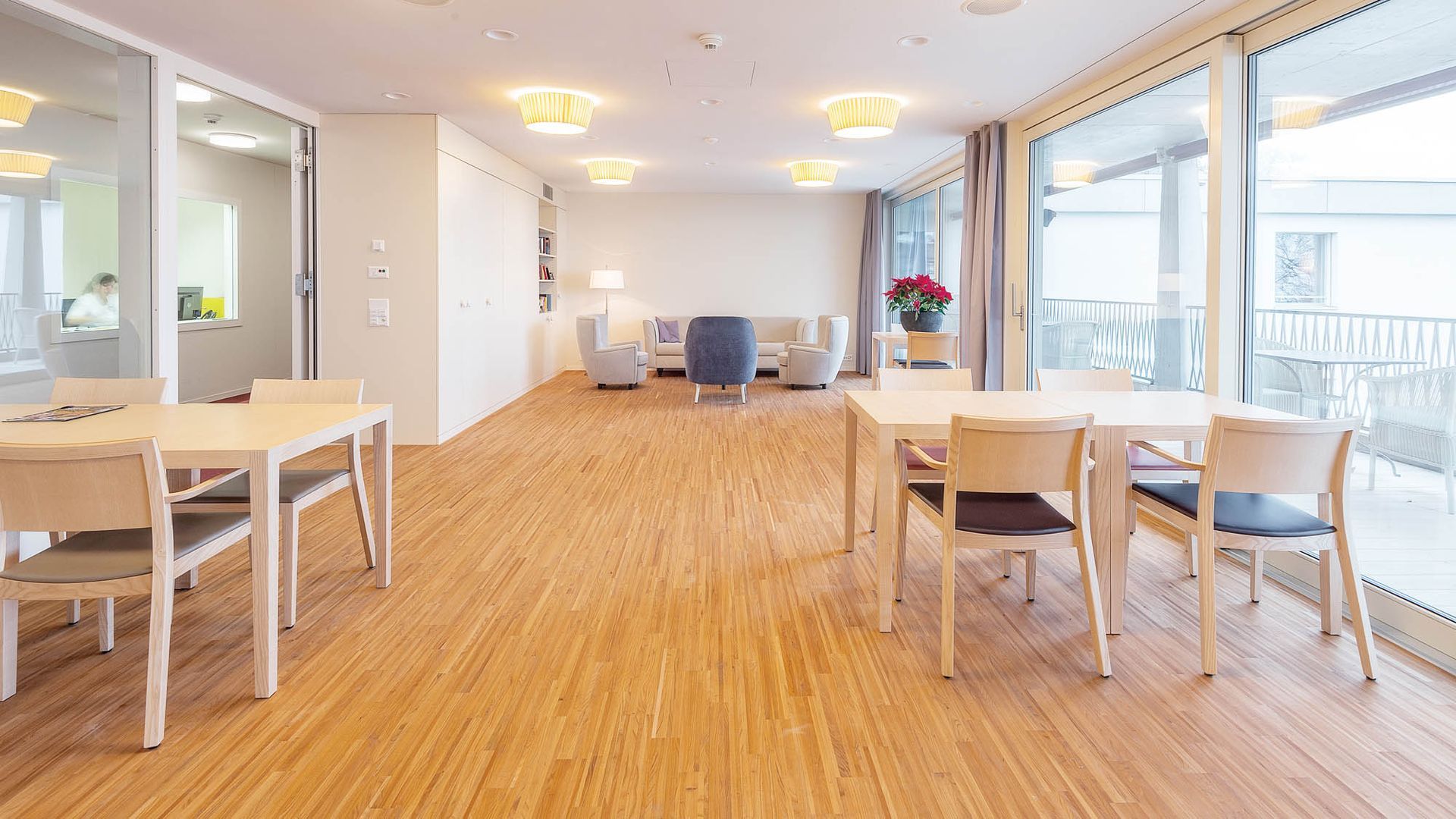 Ein großer Raum mit Holzboden und Tischen und Stühlen.