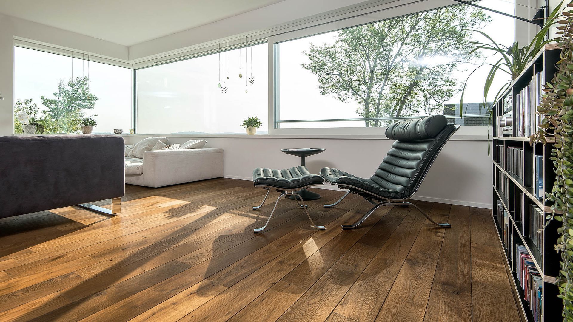 Ein Wohnzimmer mit Sofa, Sessel und Bücherregal.