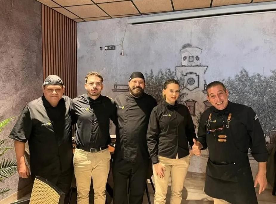 Personal del restaurante posando frente a un mural. 