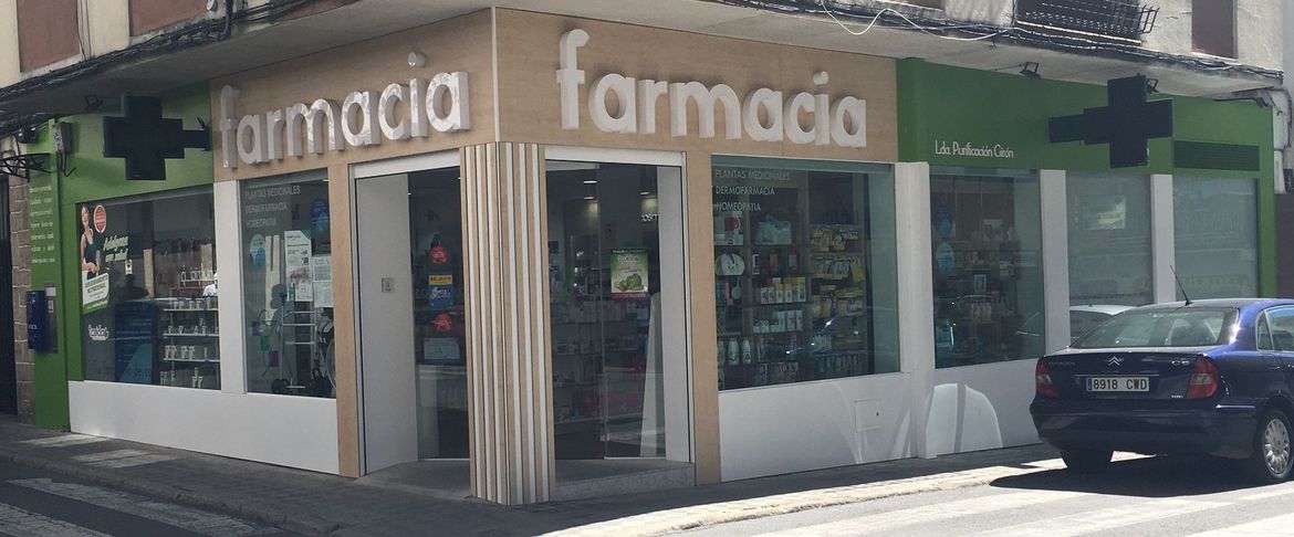 Una farmacia con un coche aparcado delante.