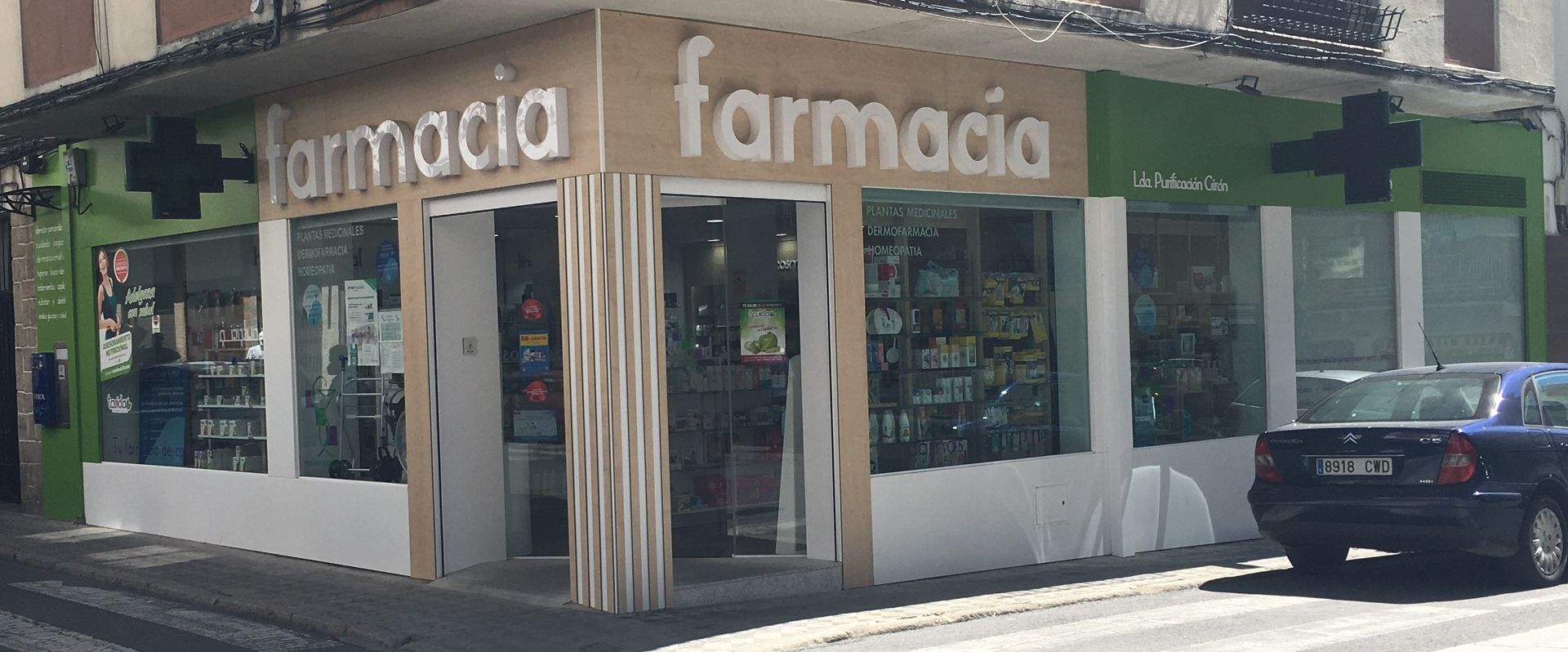 Una farmacia con un coche aparcado delante.