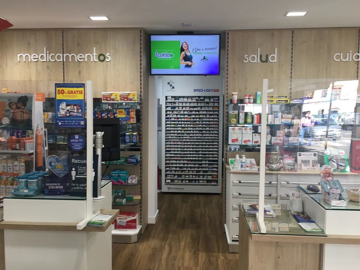 Una farmacia con una pantalla grande en la pared encima del mostrador.