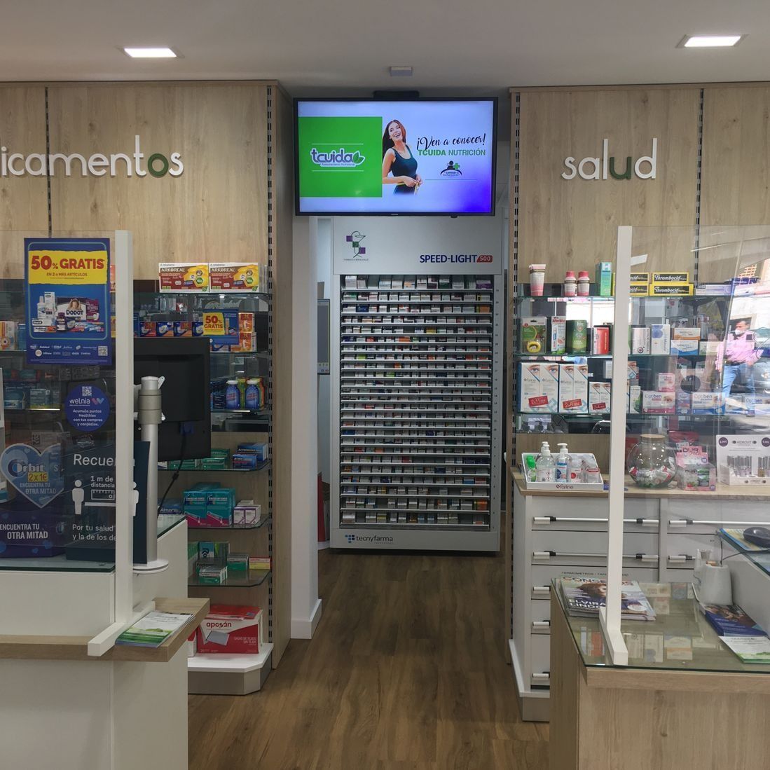 Una farmacia con una pantalla grande en la pared encima del mostrador.