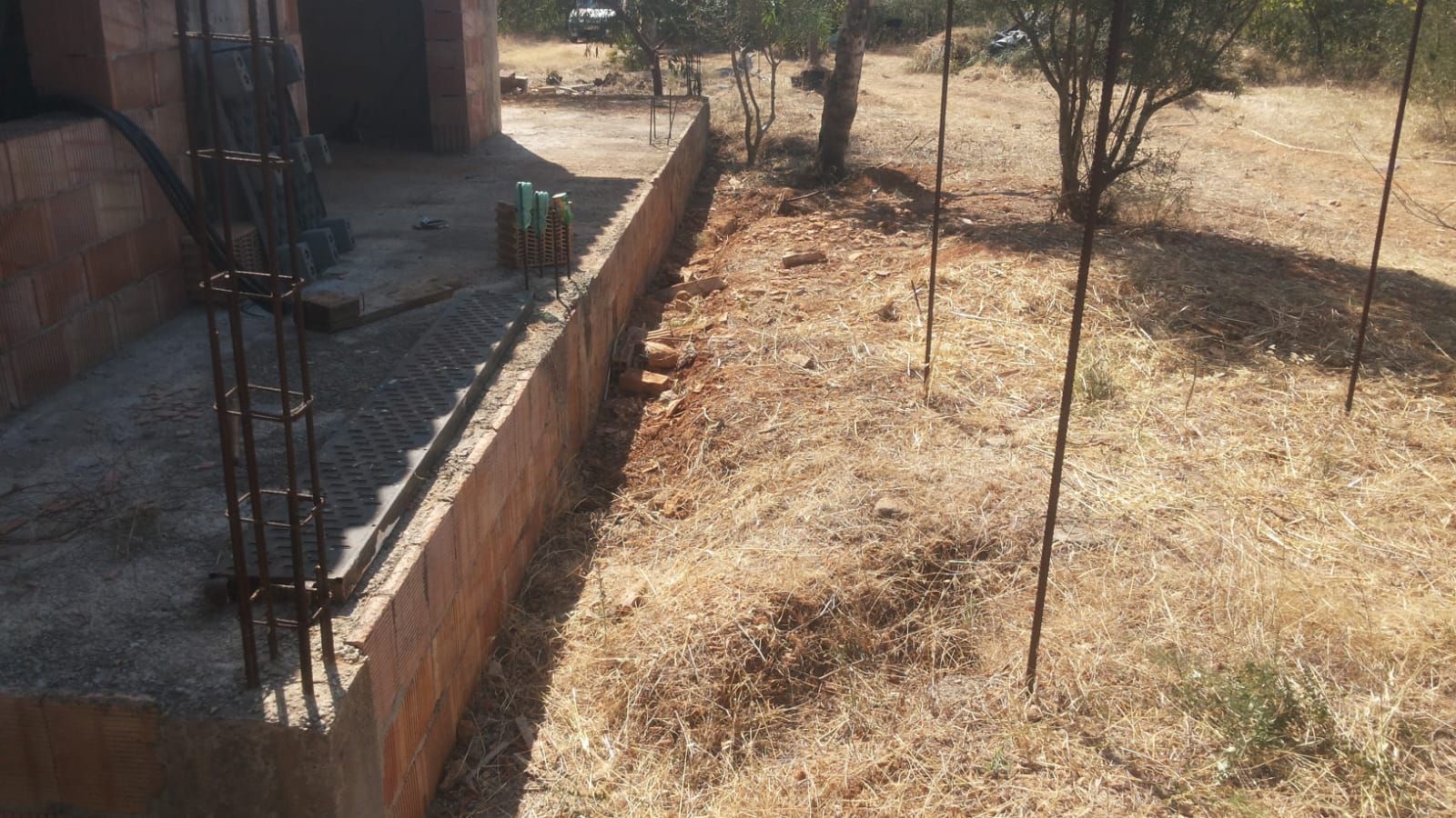 Se está construyendo un muro de ladrillos al lado de un campo de tierra.