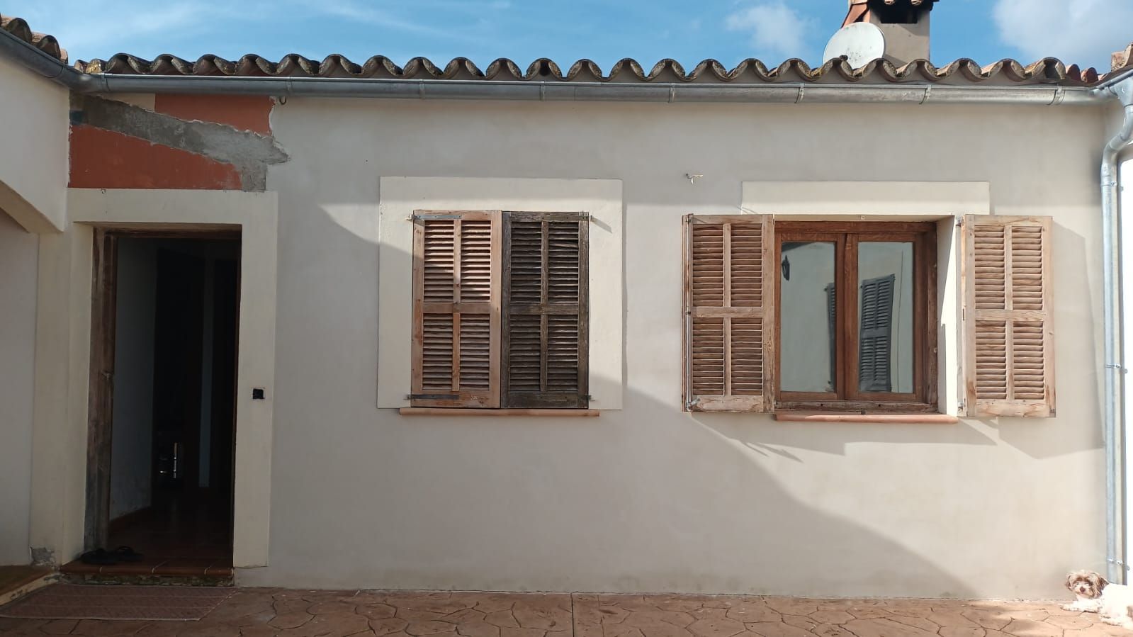 Una casa blanca con dos ventanas y contraventanas.