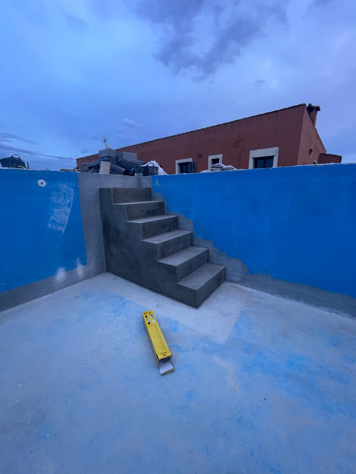 Un nivel amarillo está sentado al lado de un conjunto de escaleras en una piscina.