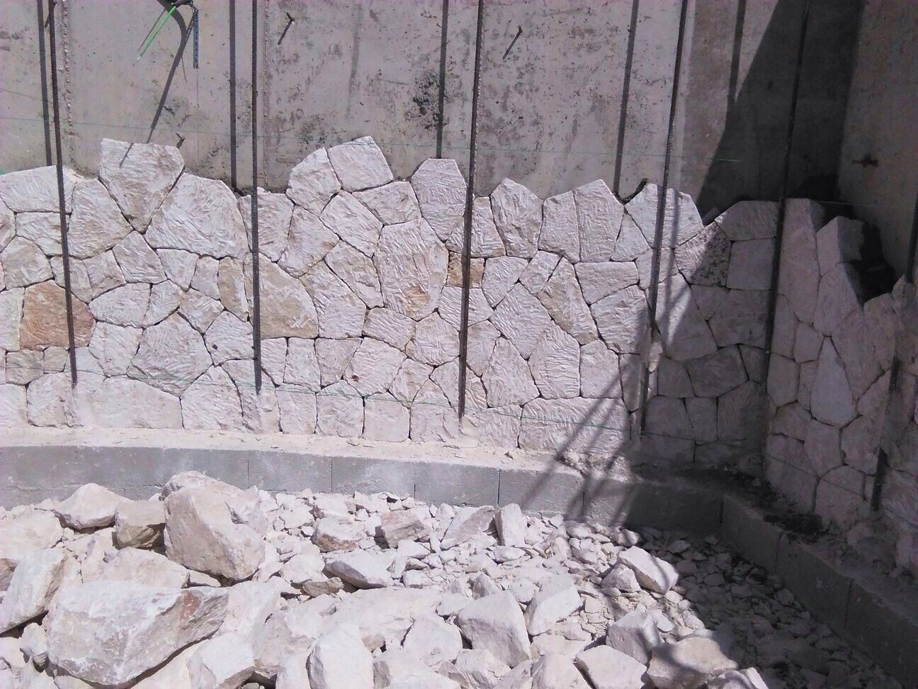 Un montón de rocas se encuentra frente a un muro de piedra.