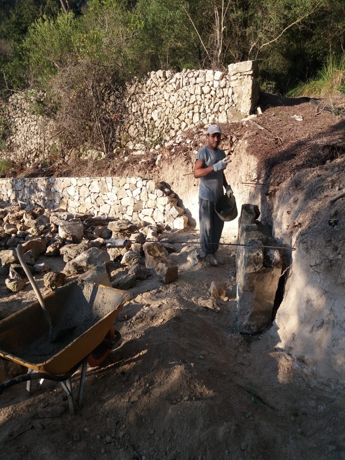 Un hombre está parado en un montón de tierra sosteniendo un cubo.