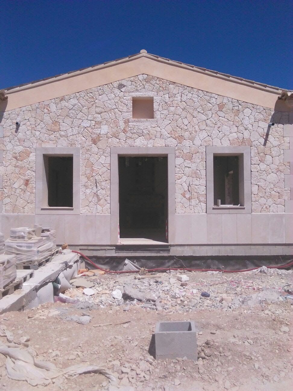 Un edificio de piedra en construcción con un cielo azul al fondo.
