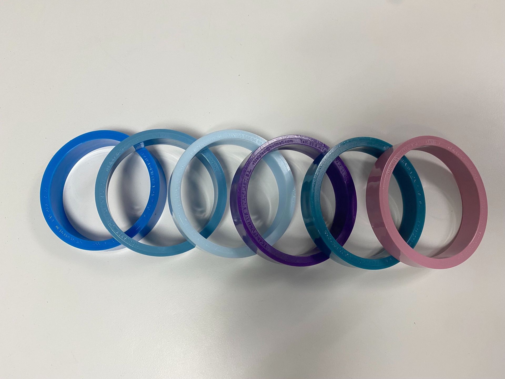 Seis anillos entrelazados, en varios tonos de azul, morado y rosa.