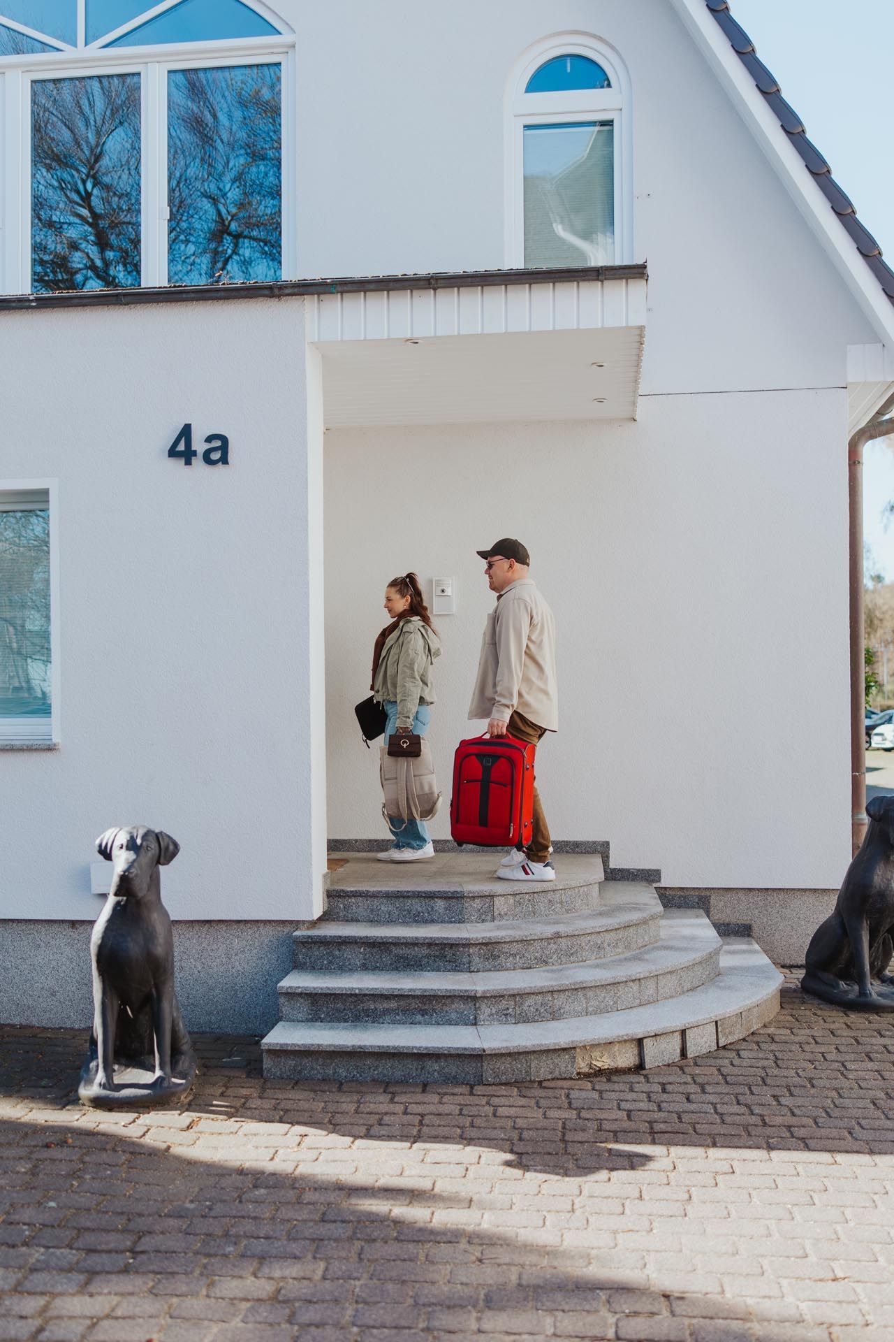 Zwei Personen unterhalten sich an einem Café-Tisch bei Tee und Gebäck an einer blau gemusterten Sitzecke.