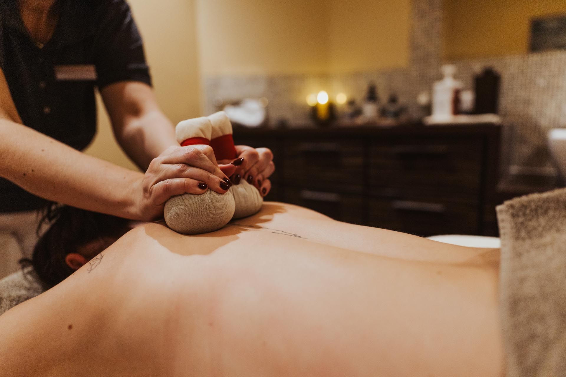 Massagetherapeut verwendet heiße Steine ​​auf dem Rücken eines Kunden in einem Spa-Umfeld