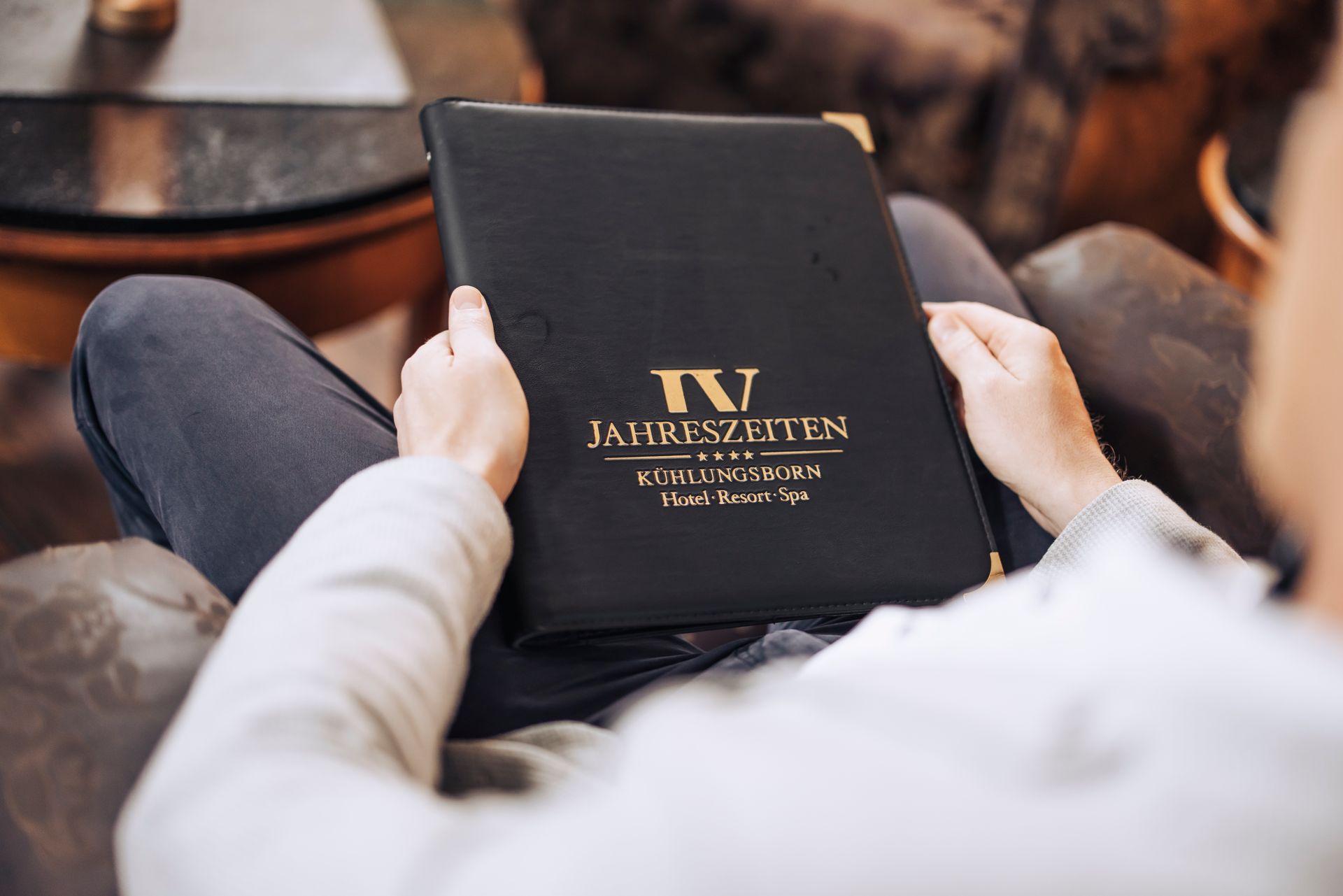 Eine Person sitzt auf einem Sofa und hält ein Buch mit der Aufschrift „IV“ in der Hand.