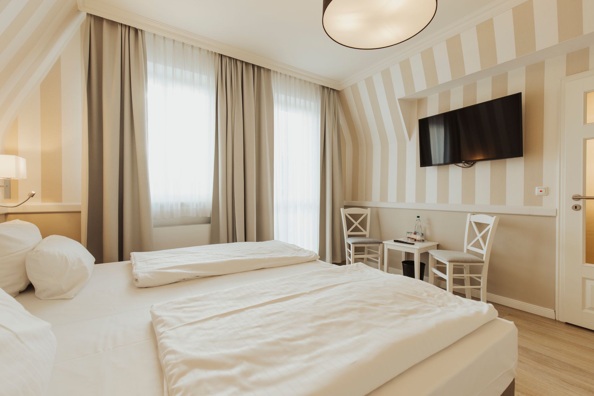 Ein Hotelzimmer mit Bett, Stühlen, Tisch und Fernseher.